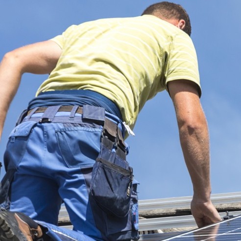 low angle view man installing solar panels roof against sky